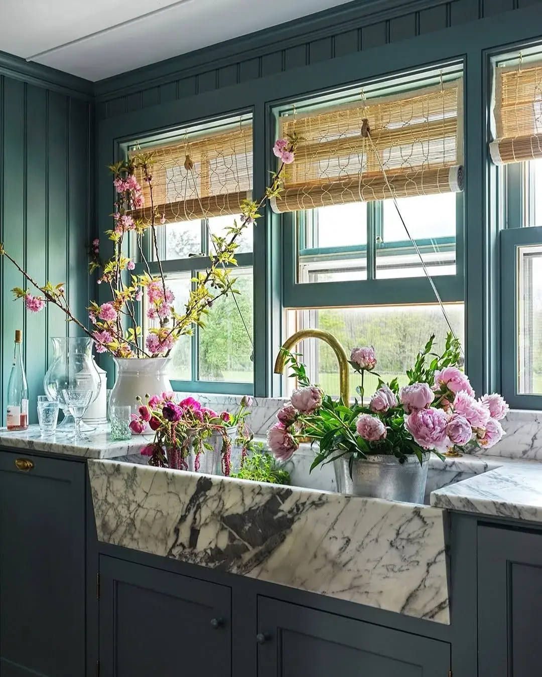 Teal green sink wall with a marble farmhouse sink, brass tap and pink blossom