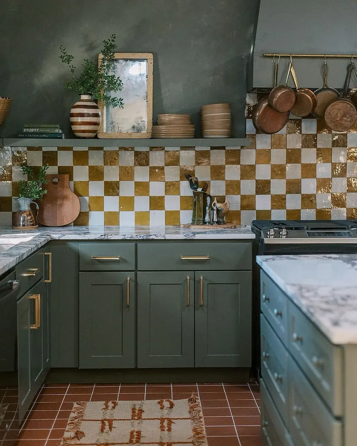 Mid olive cabinets with yellow and cream chequered tile, copper rail and terracotta floor