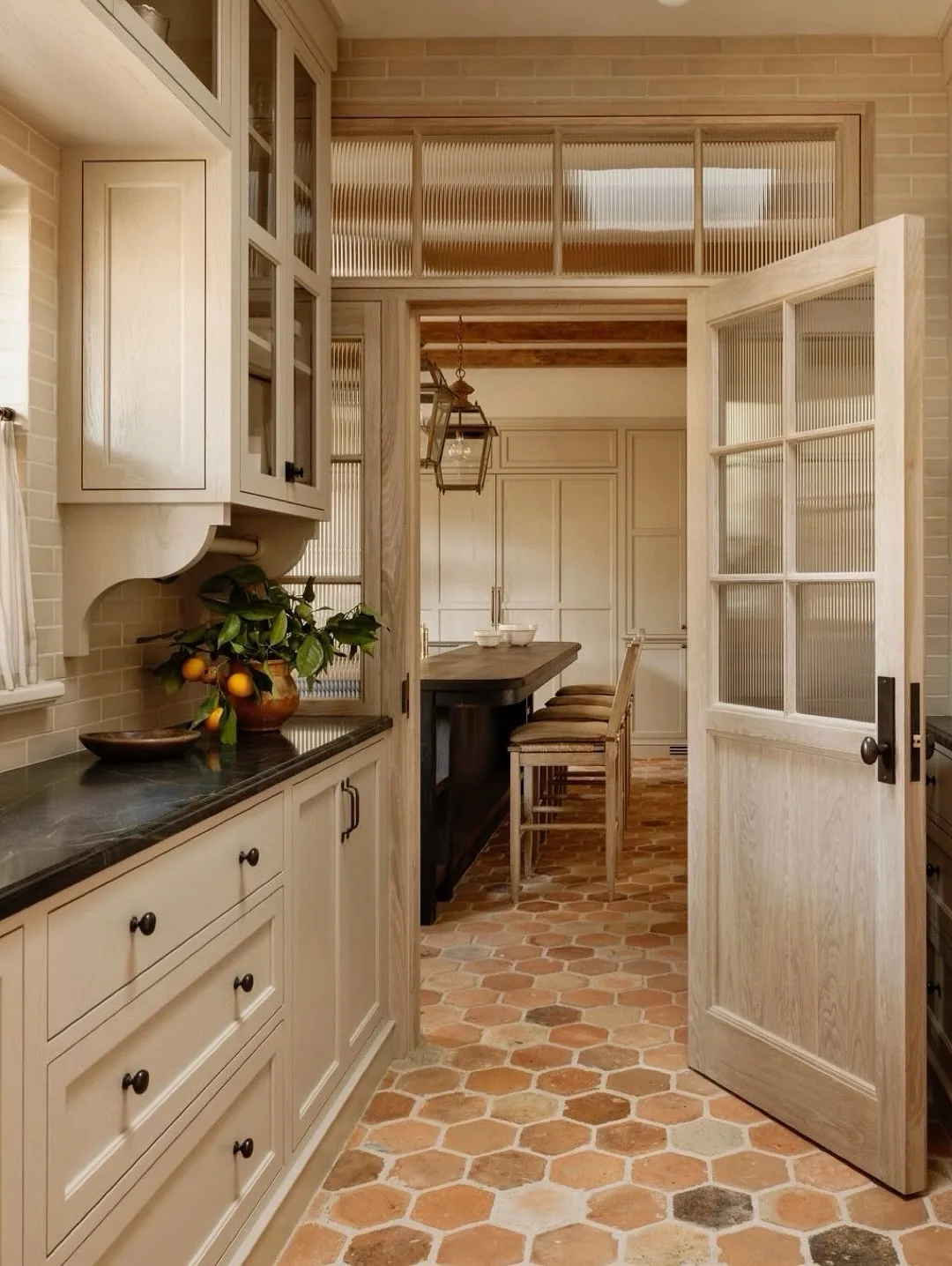 Narrow cream galley with terracotta hexagon floor and glazed doors to dining space