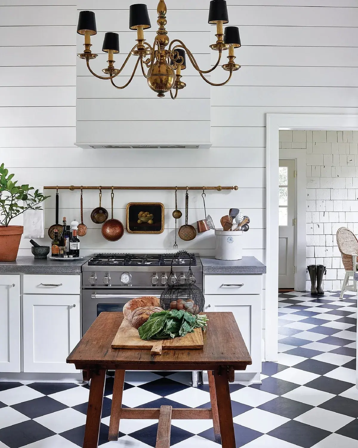 White shiplap kitchen with large black and white chequer floor and timber table