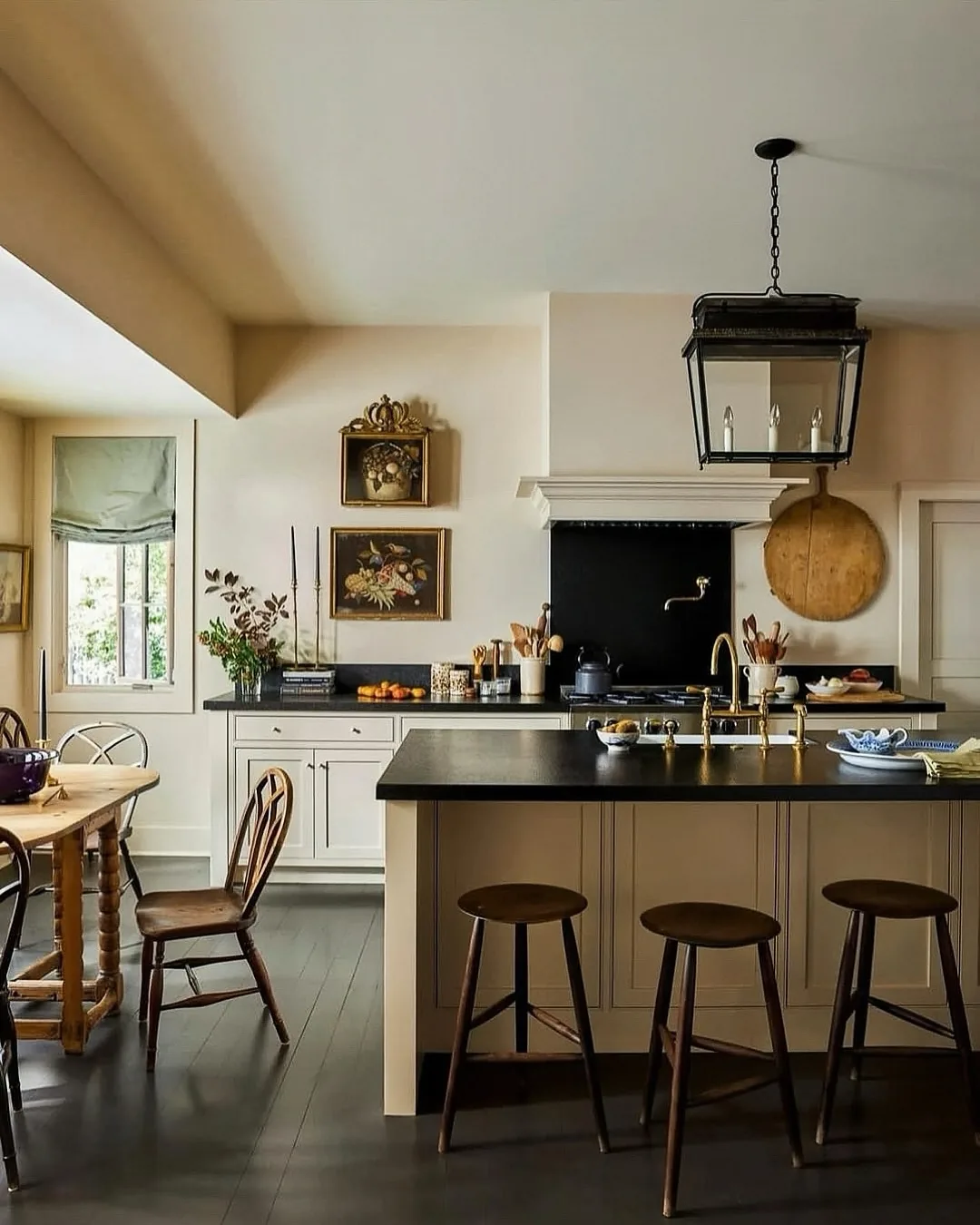 Dark island with a black countertop, timber stools and a hanging lantern