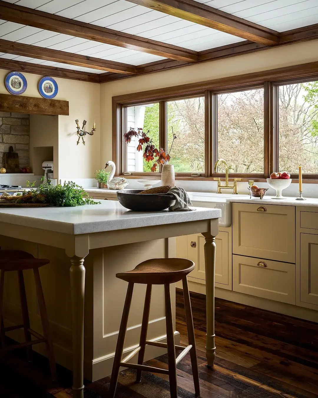 Cream kitchen with a beamed ceiling, a marble island and turned legs