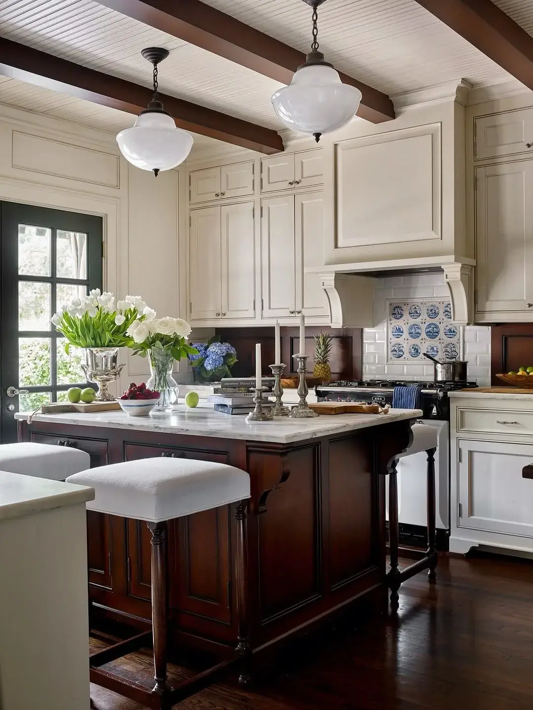 Cream kitchen with a mahogany island, turned legs and a Delft tile panel