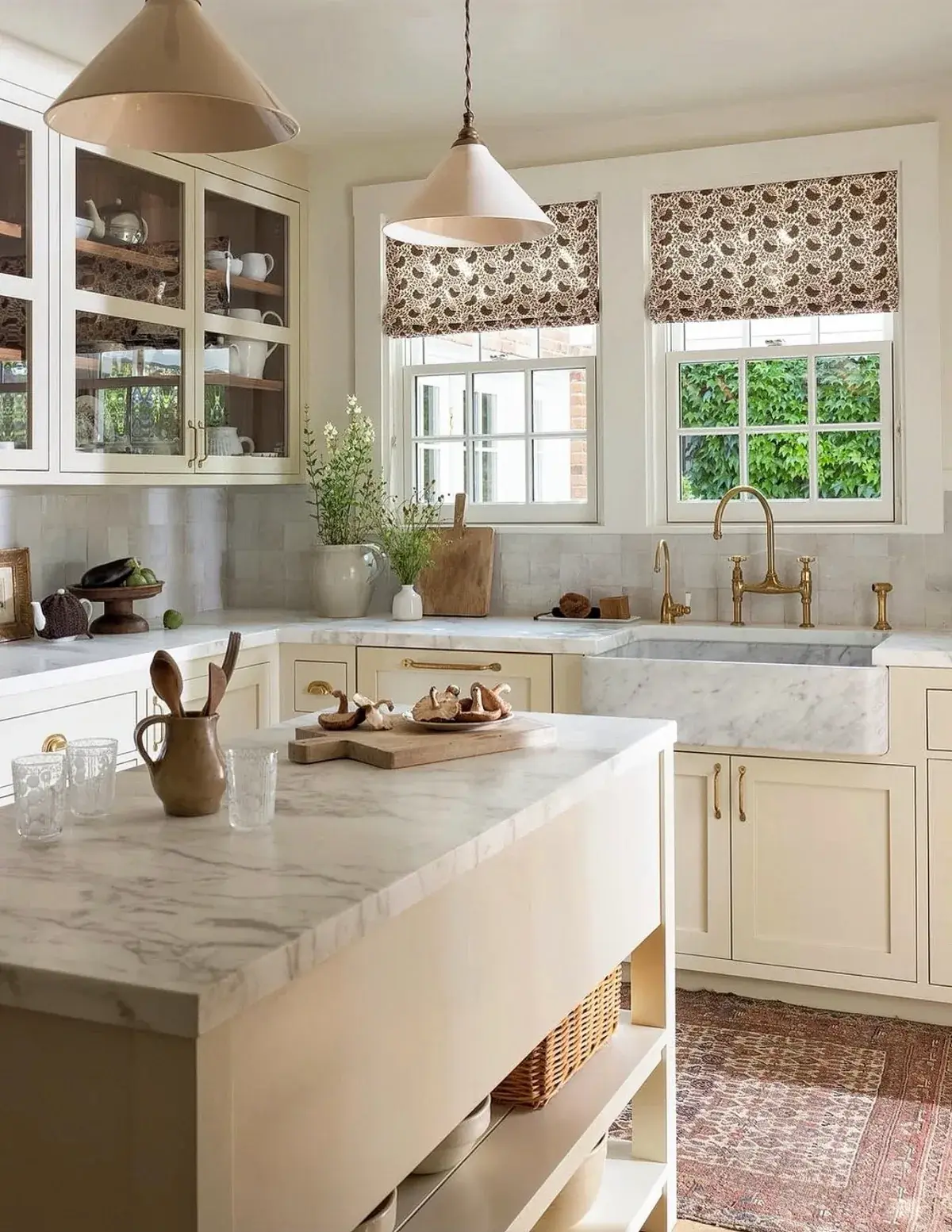 Cream kitchen with a marble island, block print shades and brass faucets