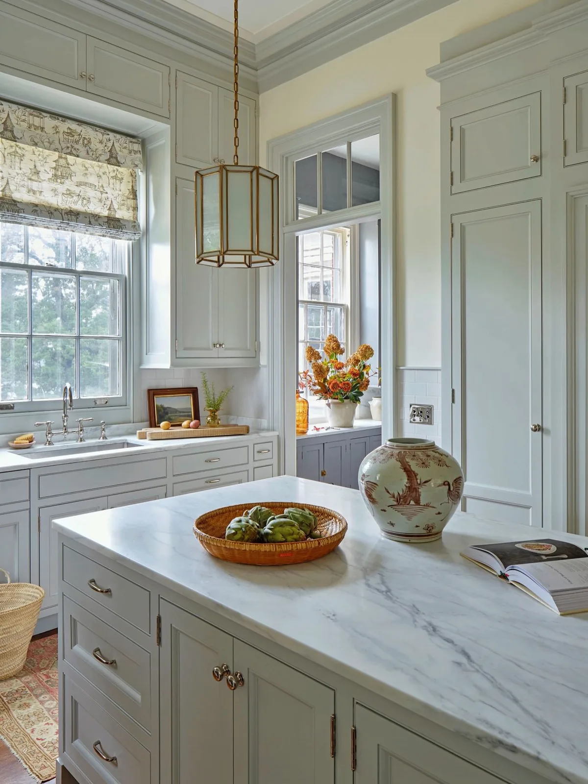 Pale gray painted island with a white marble top and a chinoiserie jar