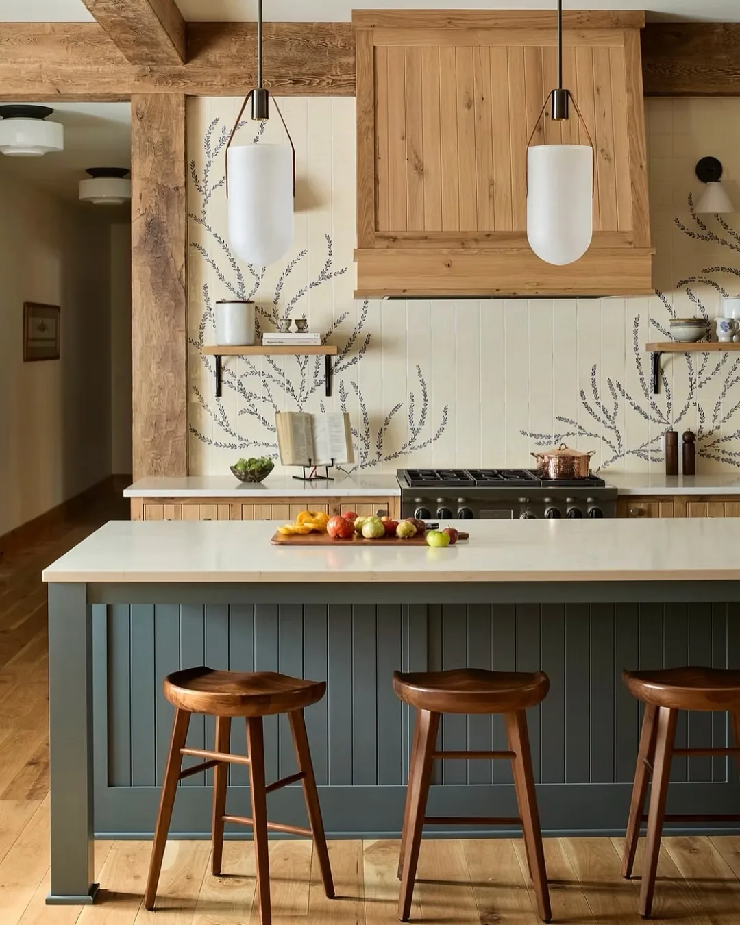 Cream kitchen with a green-blue tongue and groove island and walnut stools