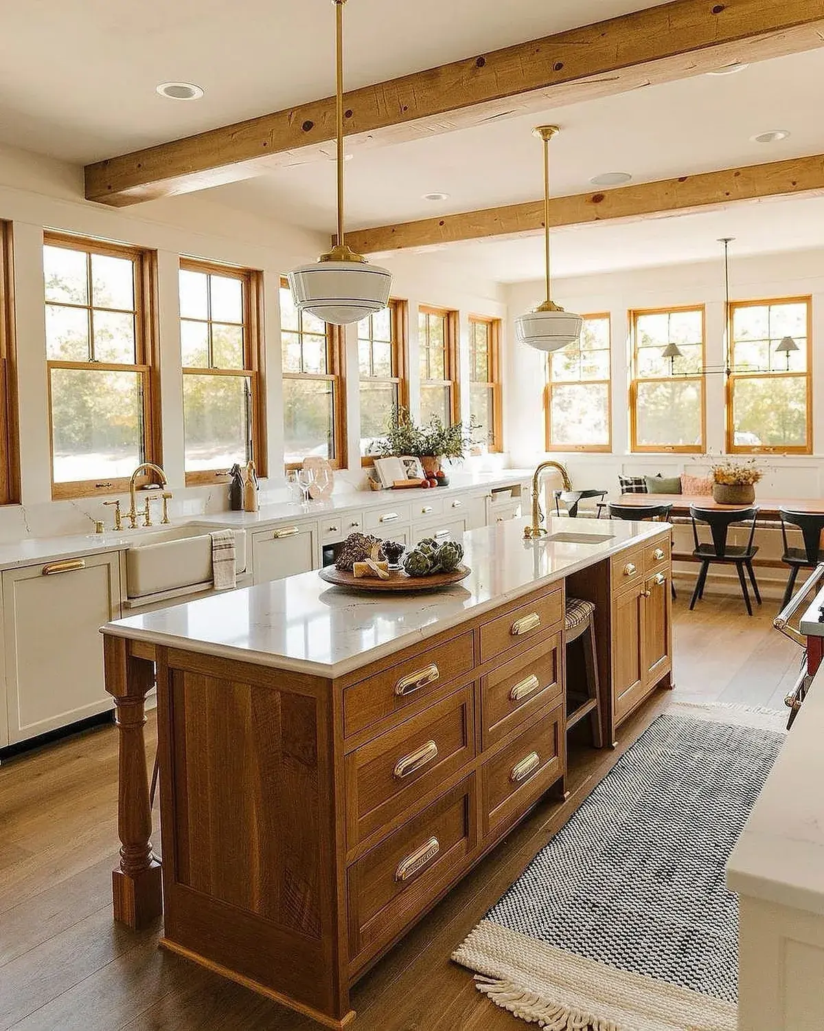 White kitchen with an oak island, twin pendants and a long window wall
