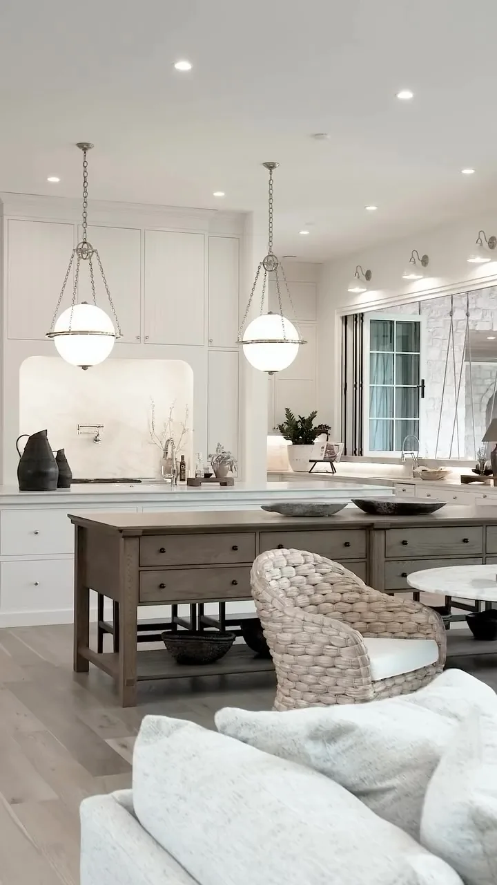 White kitchen with a timber island on an open base and globe pendants