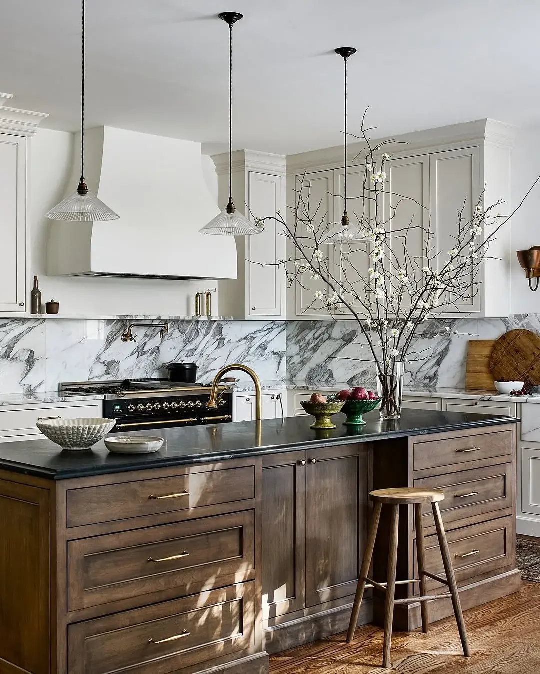 White kitchen with a heavily veined marble splashback and a dark island with a black stone top
