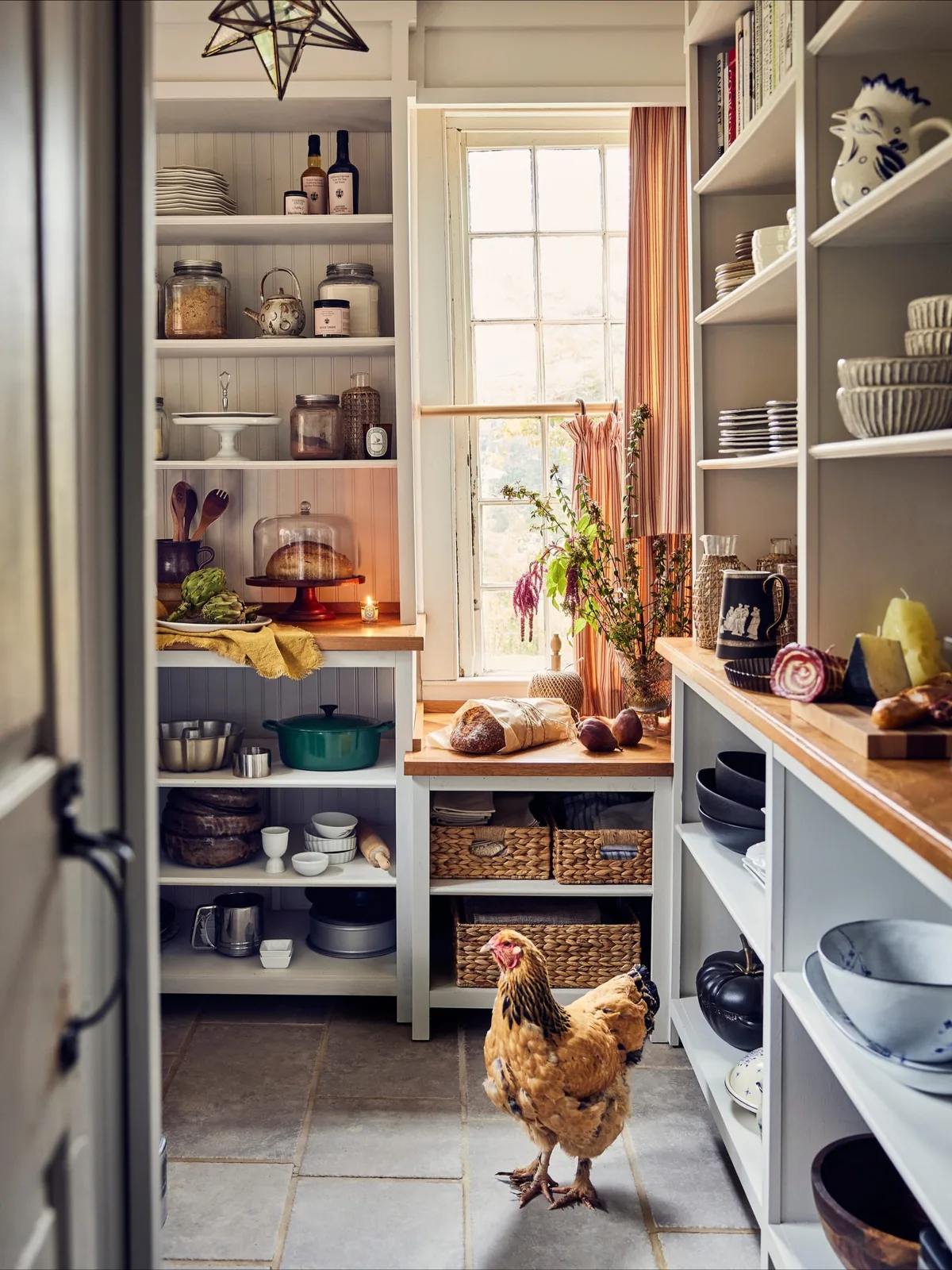 Small pantry with full open shelves on three sides around a window
