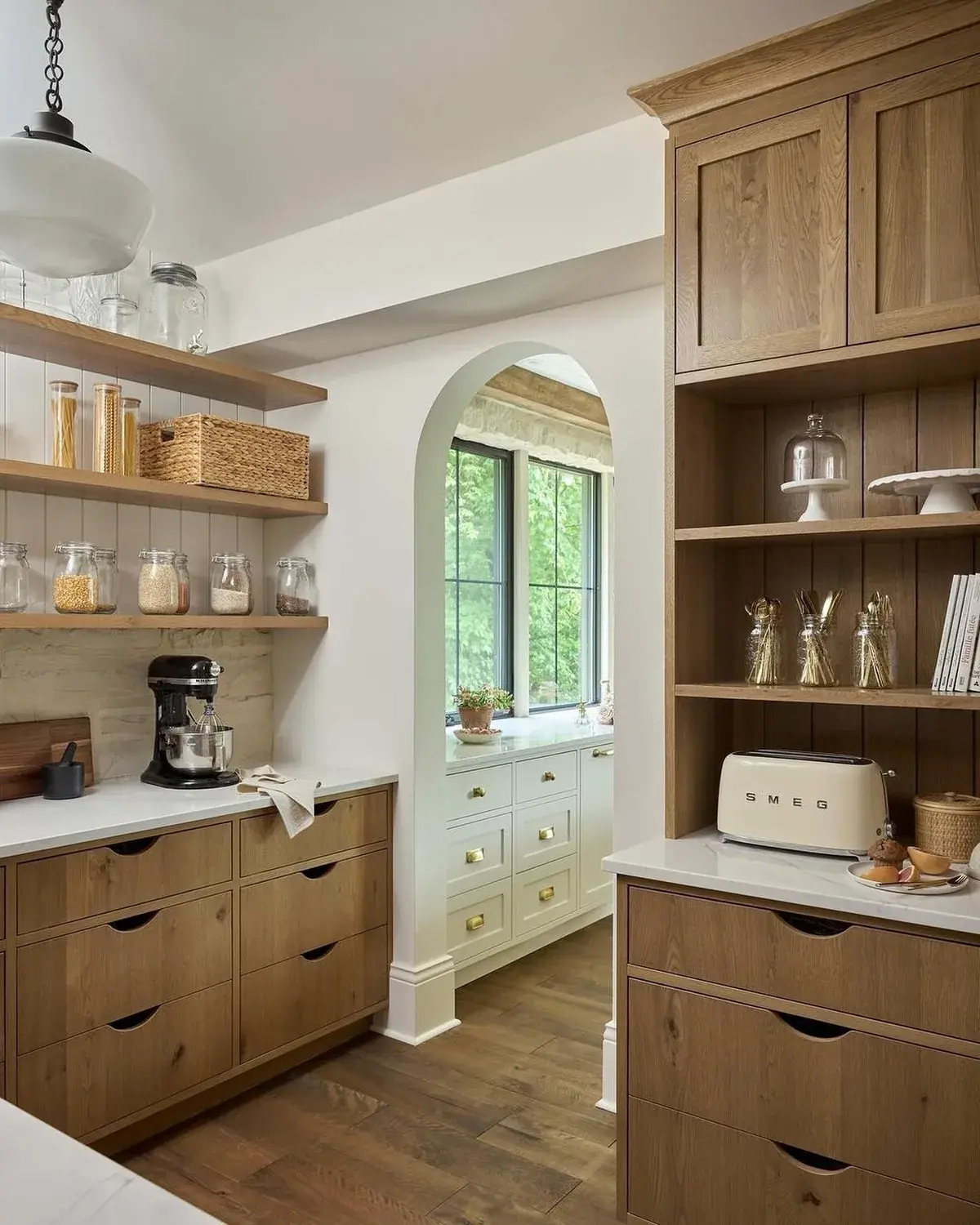 Oak shelves with glass storage jars and baskets above a worktop with a stand mixer