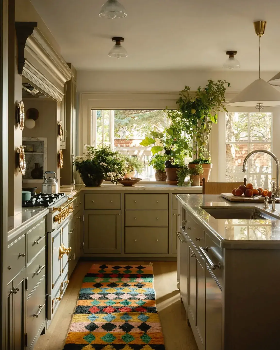 Sage kitchen with a brass-trimmed range, antique copper moulds and a bright rag runner