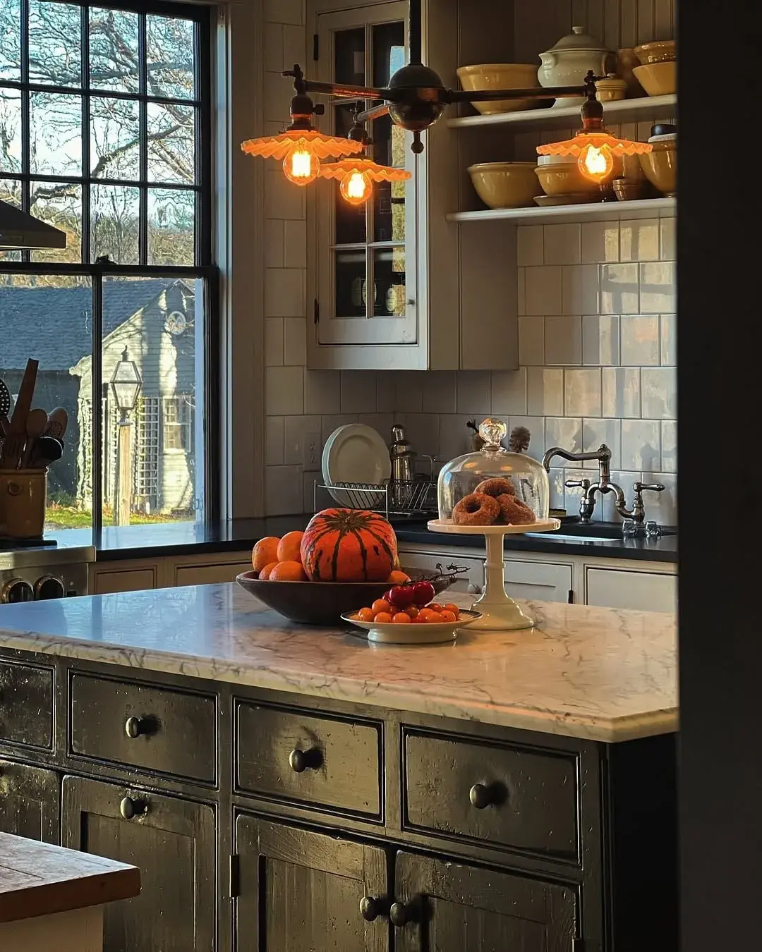 Kitchen island with a dark green painted base, marble top and amber glass wall lights