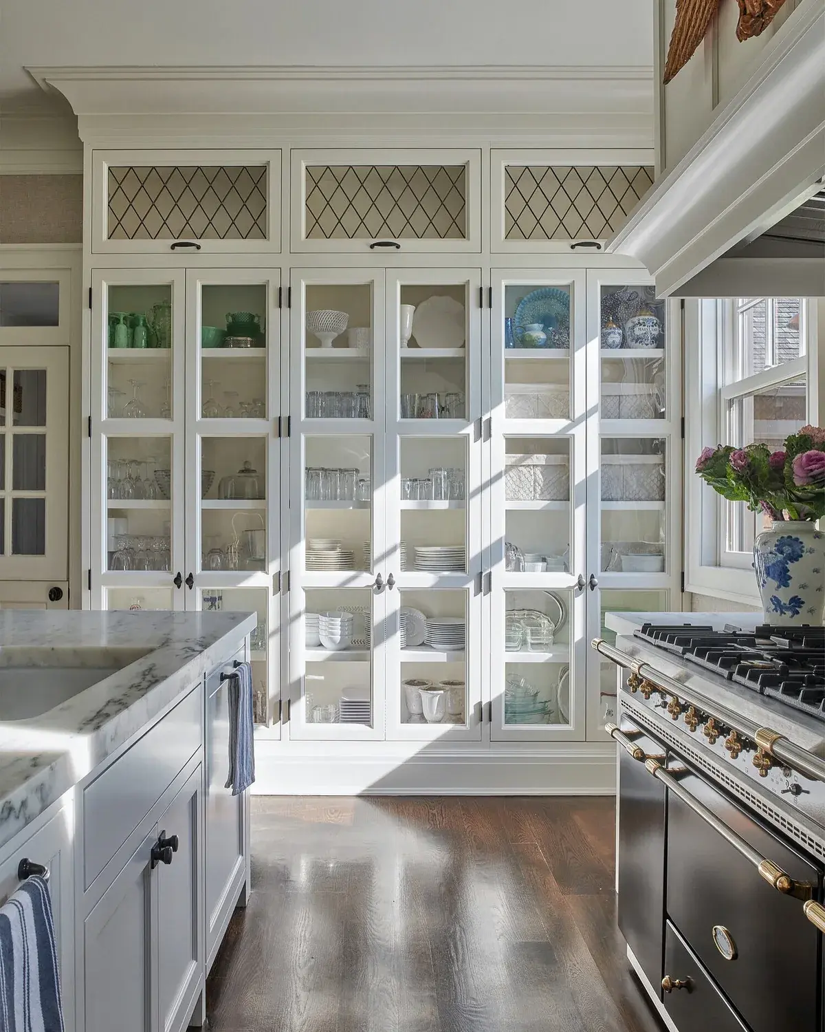 White glazed cabinets with diamond top lights, dark floor and a black range cooker