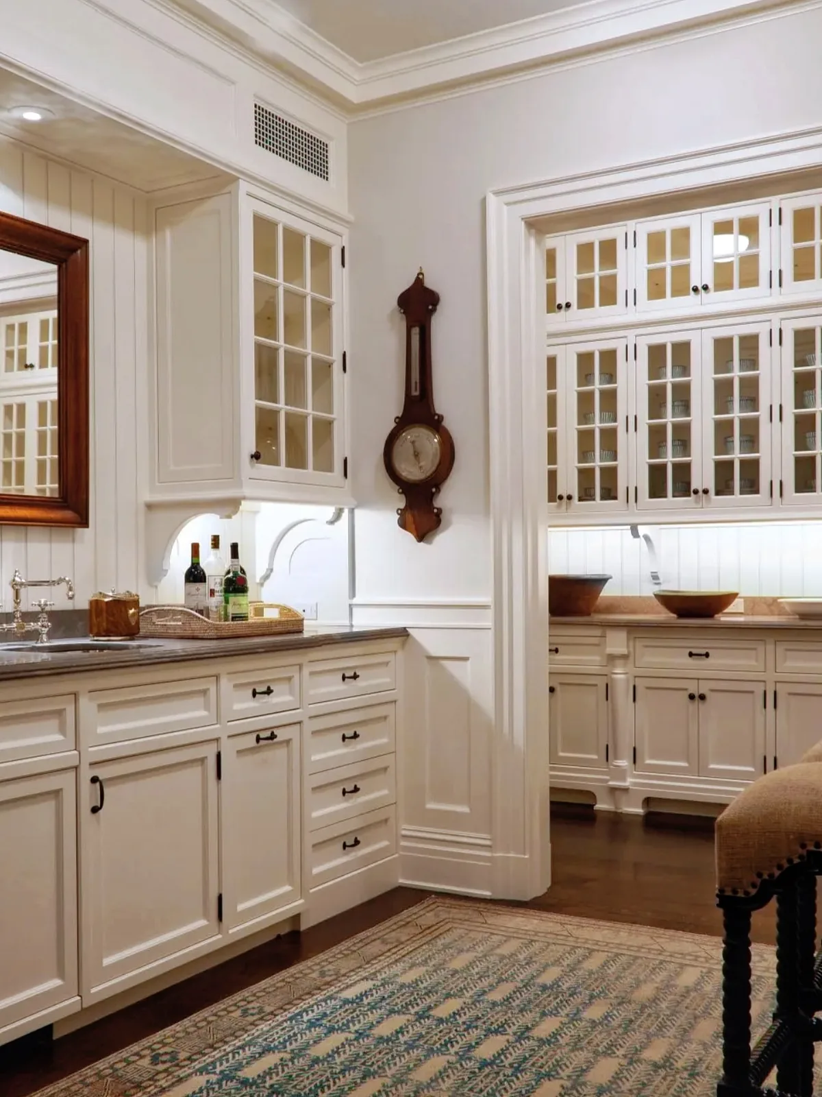White pantry with glazed cupboards, a wall barometer, runner rug and warm strip light