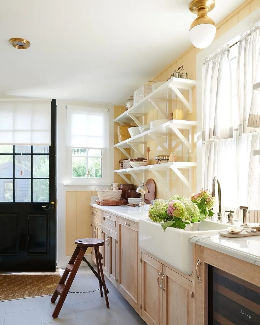 Pale oak kitchen with white open shelves, black door and wooden steps