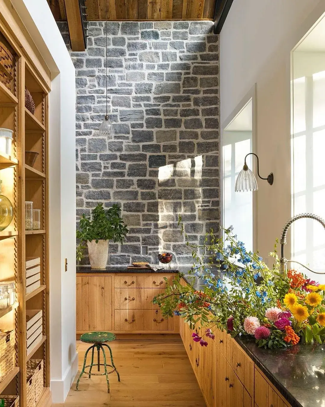 Knotty pine units against a tall grey stone wall with dark tops