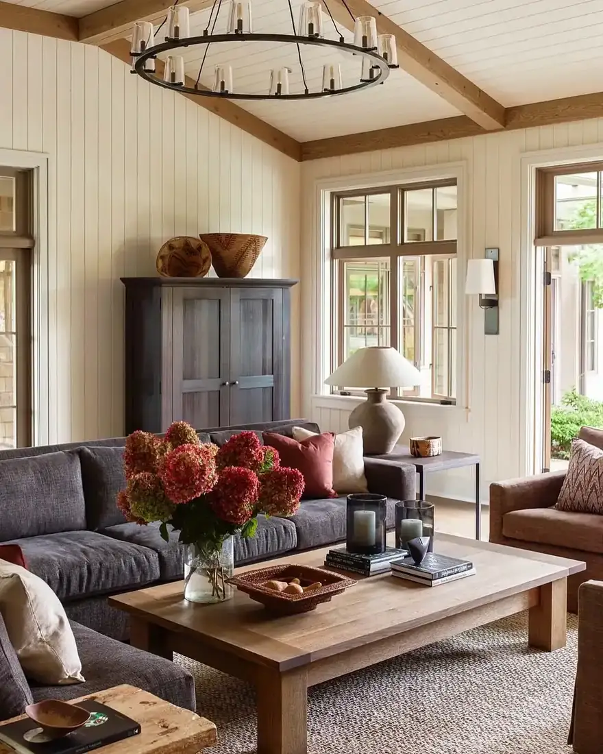 Vaulted living room with pale timber beams, white tongue and groove walls and a dark sofa