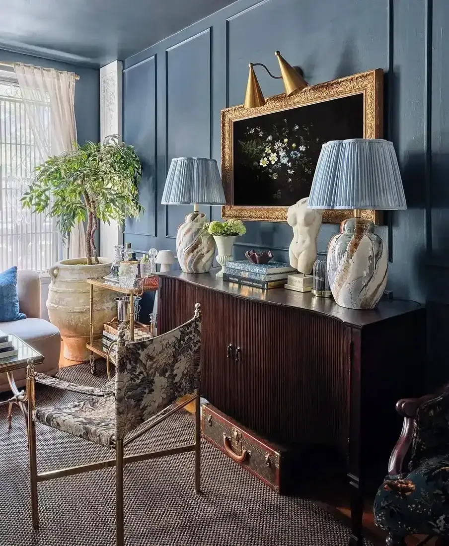 Living room corner with dusty blue panelled walls, fluted sideboard and pleated lampshades