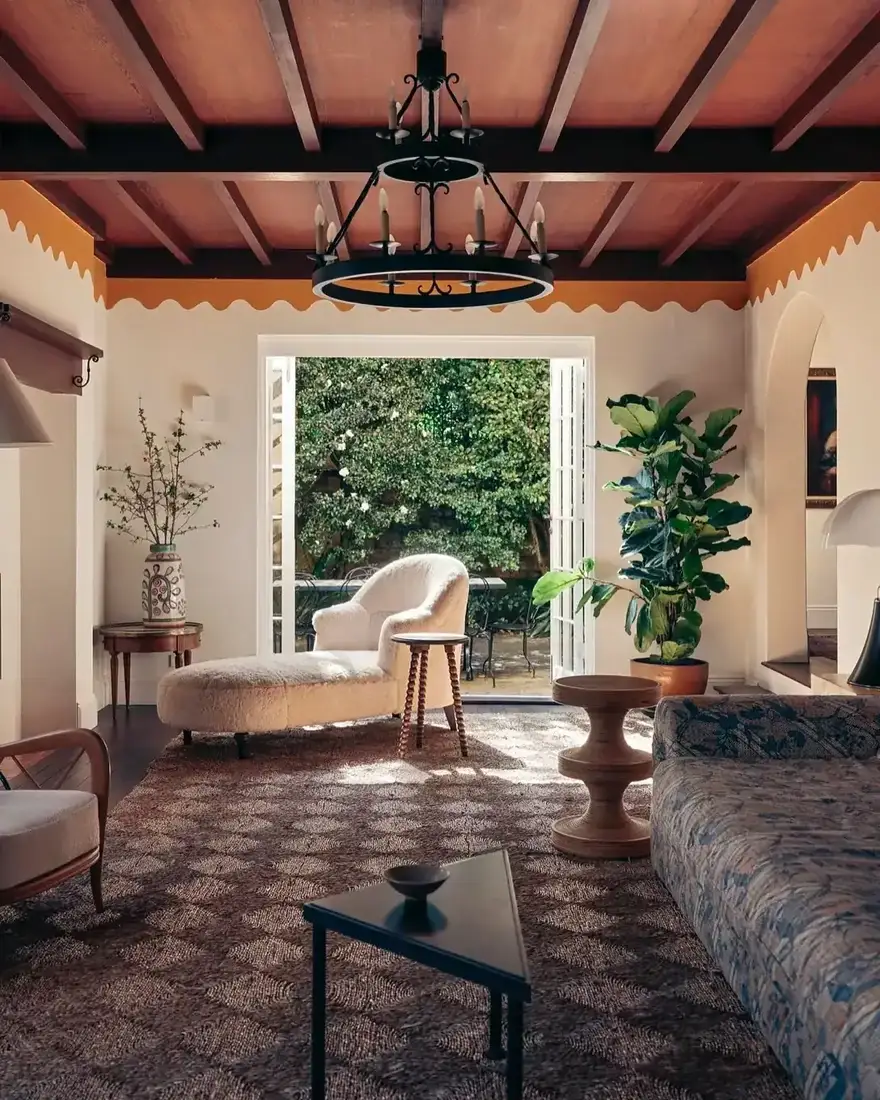 Sitting room with dark timber beams, terracotta boards and a boucle chaise by open garden doors