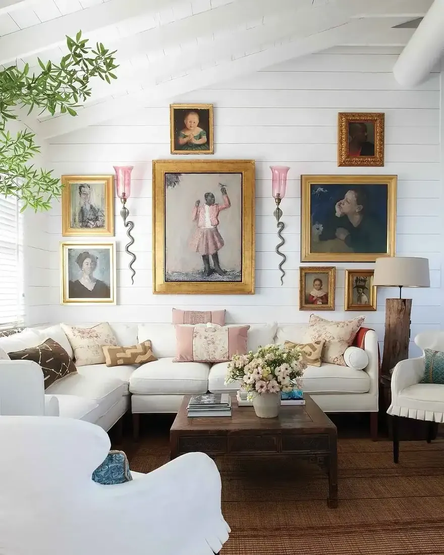 White shiplap sitting room with a gilt portrait gallery hung low over a white sectional