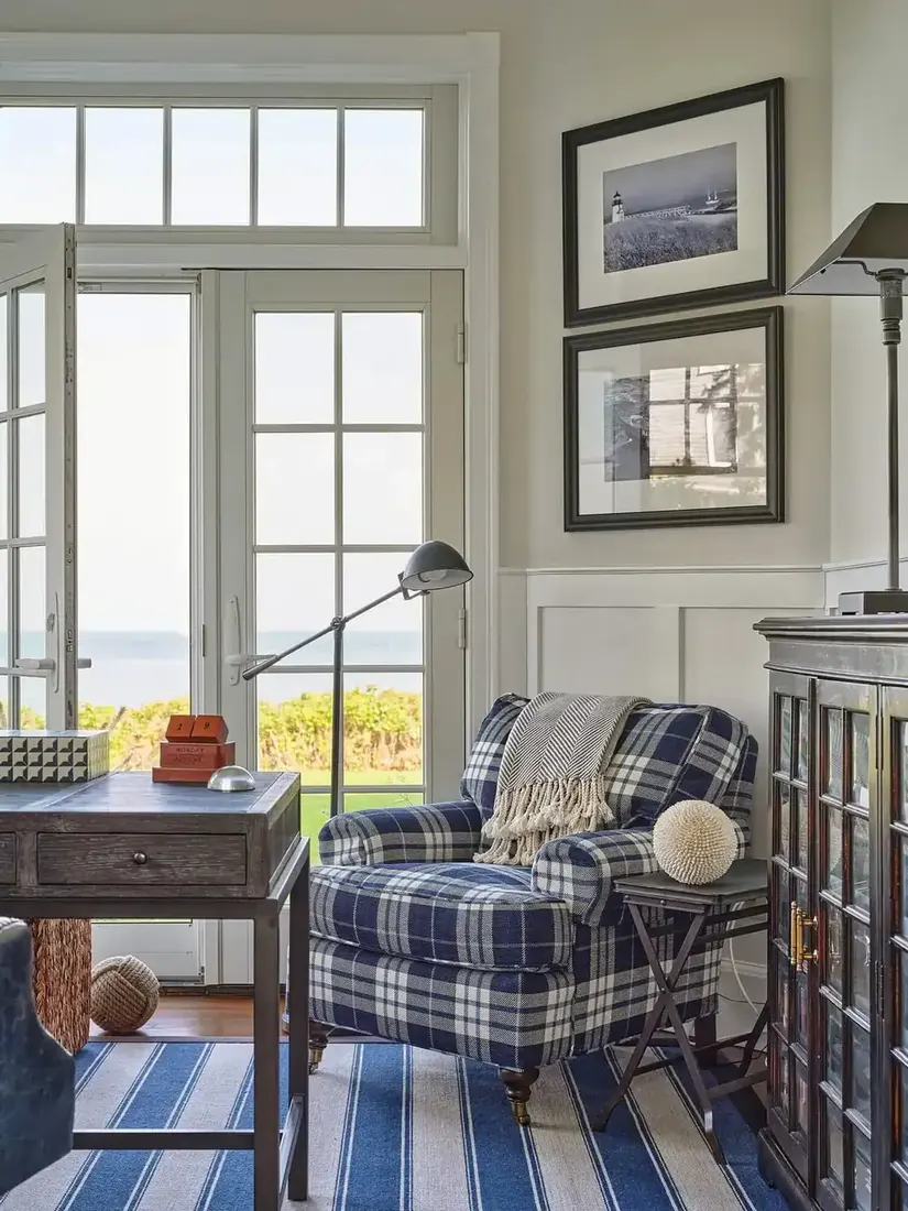 Navy plaid armchair beside dark timber desk with sea view doors