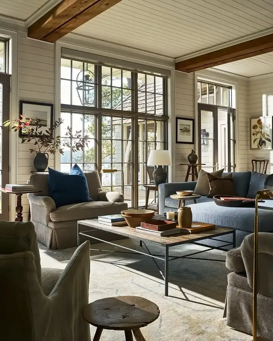Lake house sitting room with steel windows, blue sofa and timber beams