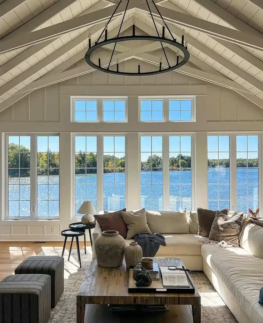 Vaulted white living room with lake view, white sofas and timber table
