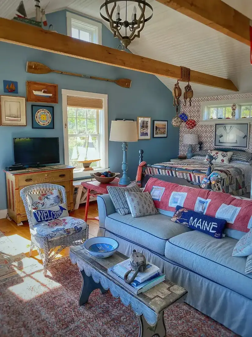 Small blue walled living room with pine dresser, red table and wicker chair