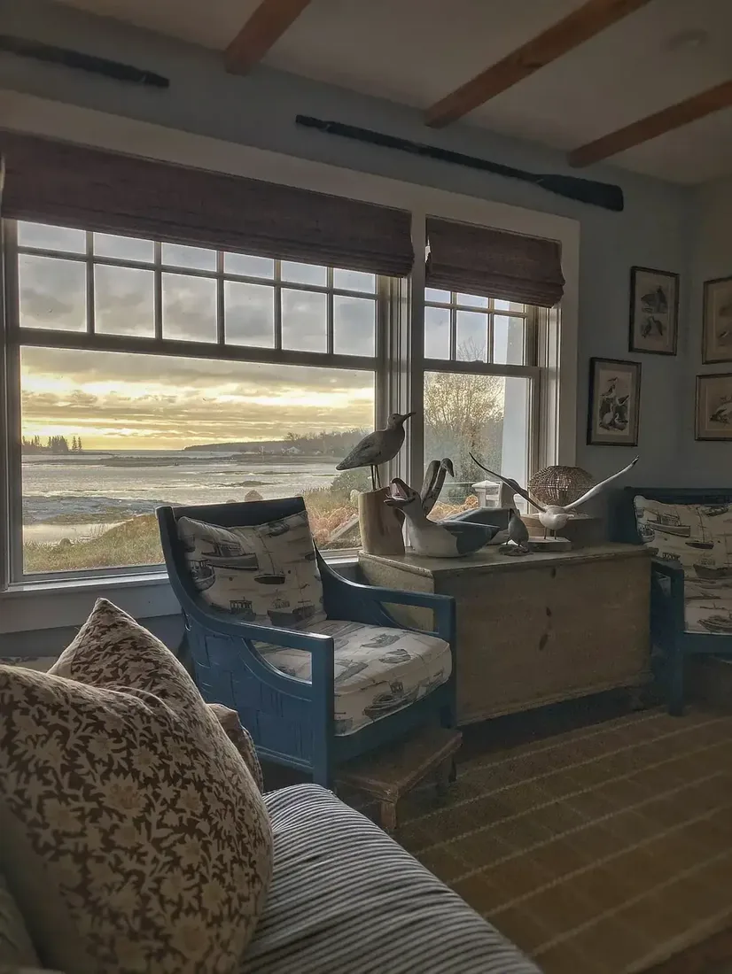 Blue painted armchairs with boat print beside timber chest at sunset