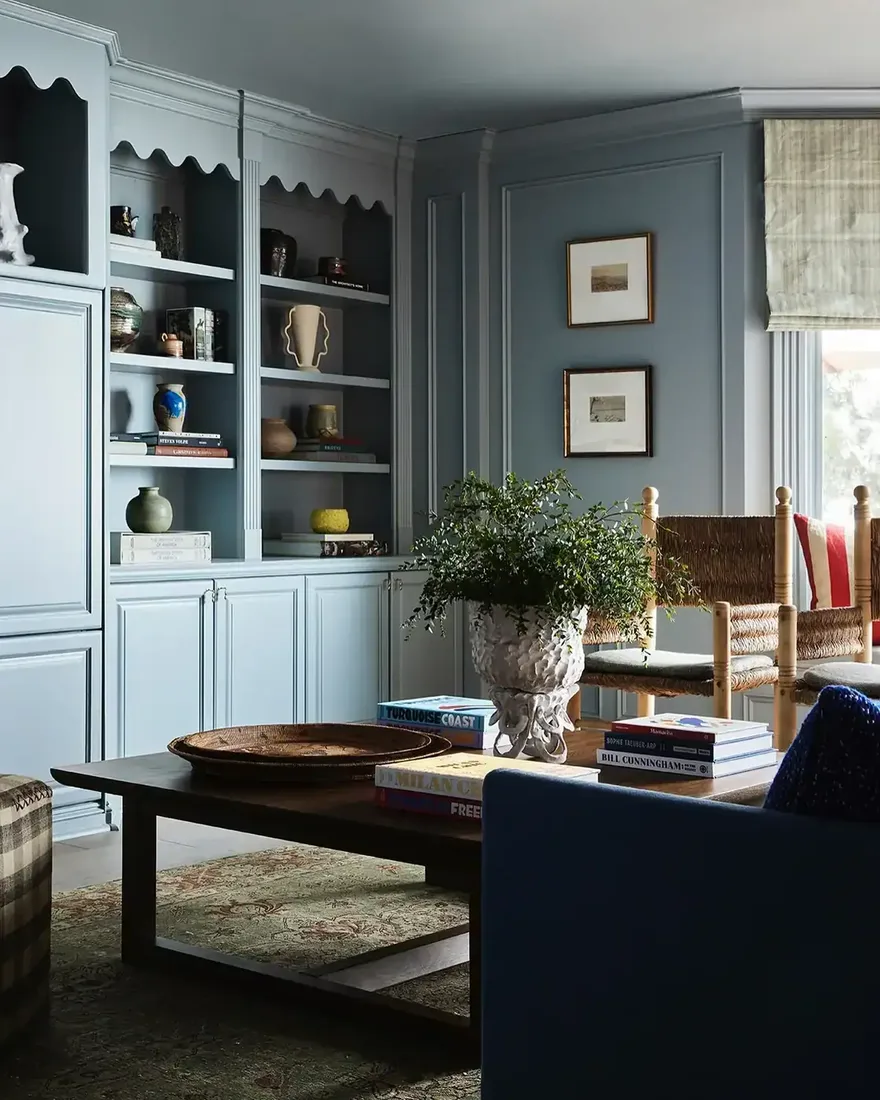 Blue-grey built-in shelves with scalloped valances above closed cupboards