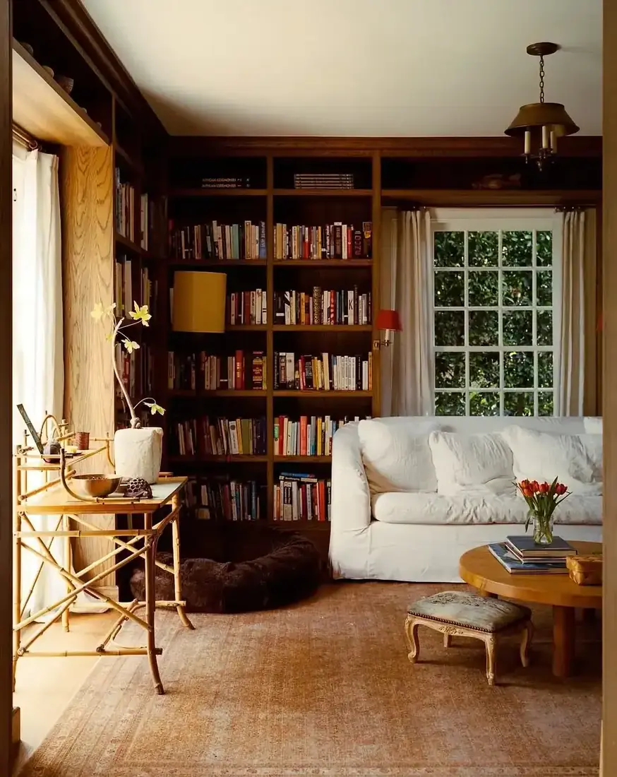 Dark stained timber built-ins packed with books around a window