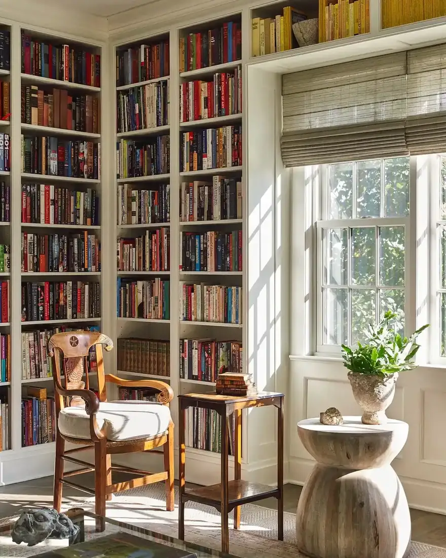 White corner built-ins packed with colourful books around an armchair