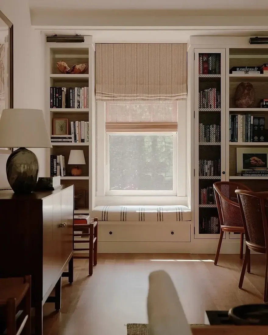 White built-ins around a window seat with striped cushion and glass doors