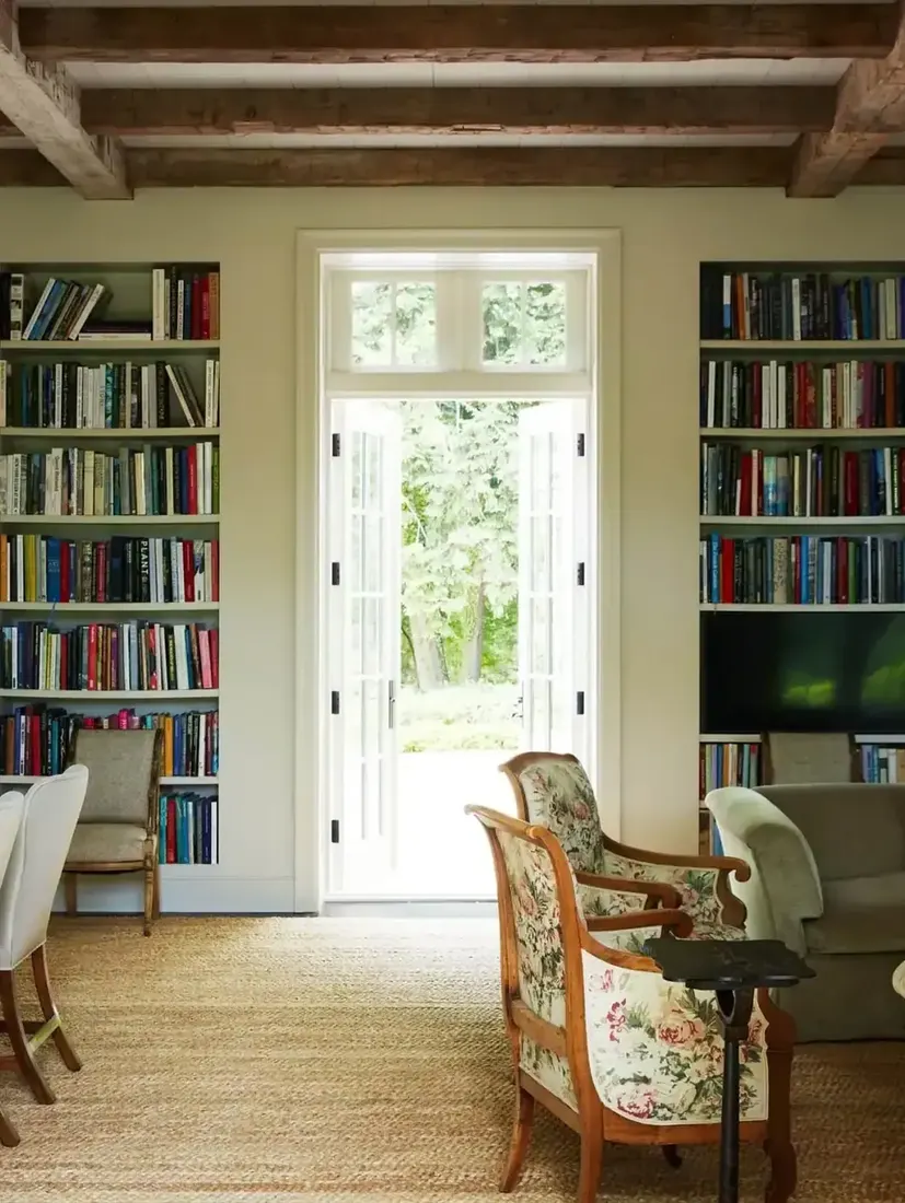 White built-ins either side of French doors with a television inside the shelving
