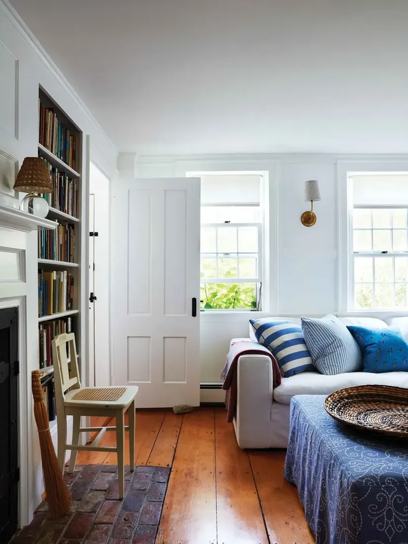 White slipcovered sofa with three blue patterned pillows and pine floor