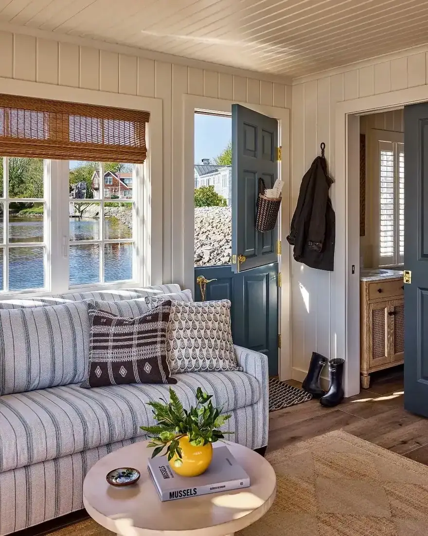 Striped sofa with dog, shell bowl and botanical prints in coastal room
