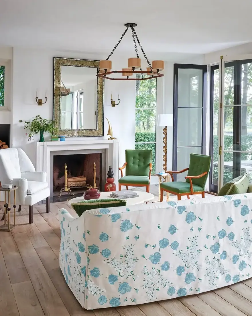 Blue floral skirted sofa facing a pair of green velvet chairs in a white room