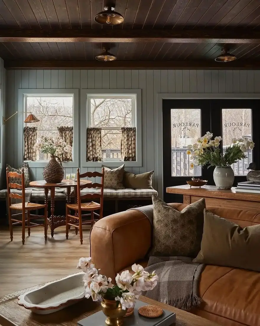 Tan leather sofa in a beamed room with pine table and window seat