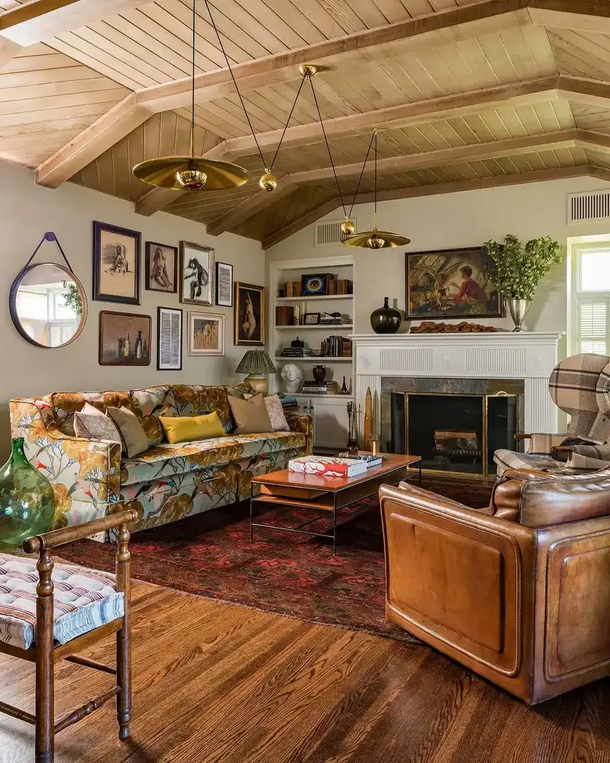 Bold floral sofa with leather chairs under a vaulted beamed ceiling