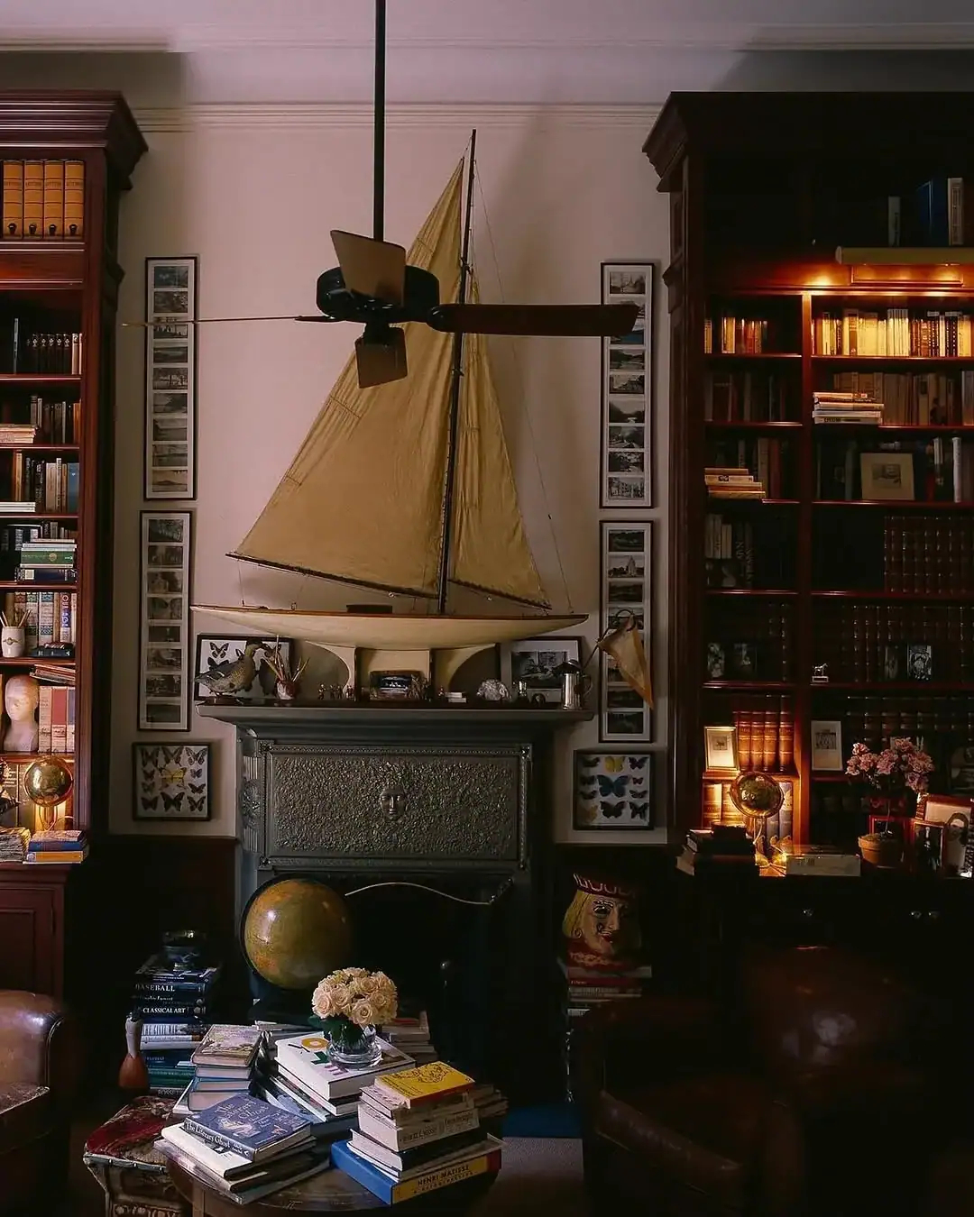 Two freestanding mahogany bookcases flanking a cast iron fireplace, lit from inside