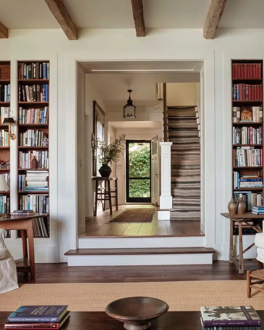 Narrow white bookshelves standing flush either side of a wide cased opening