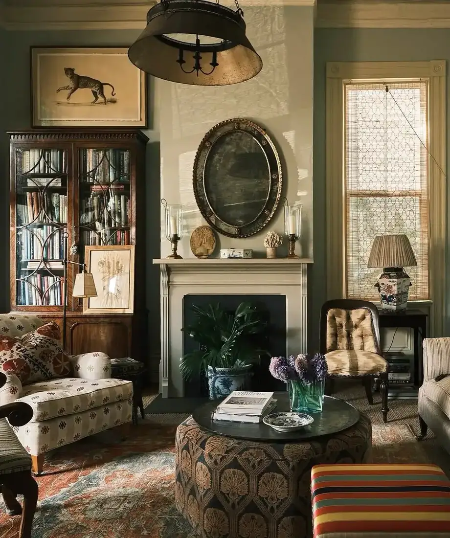 Cream fireplace with an oval mirror, a pair of hurricane lamps and small fossils on the mantel