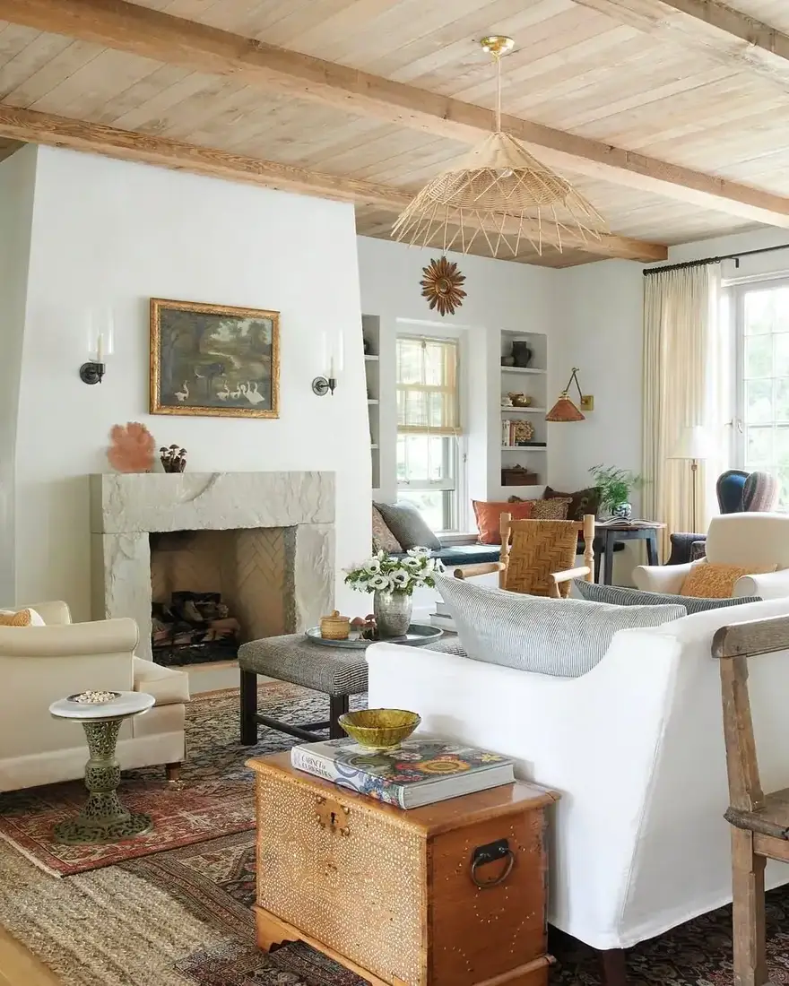White plaster fireplace with a thick stone mantel dressed with a duck painting, sconces and small bowls at one end