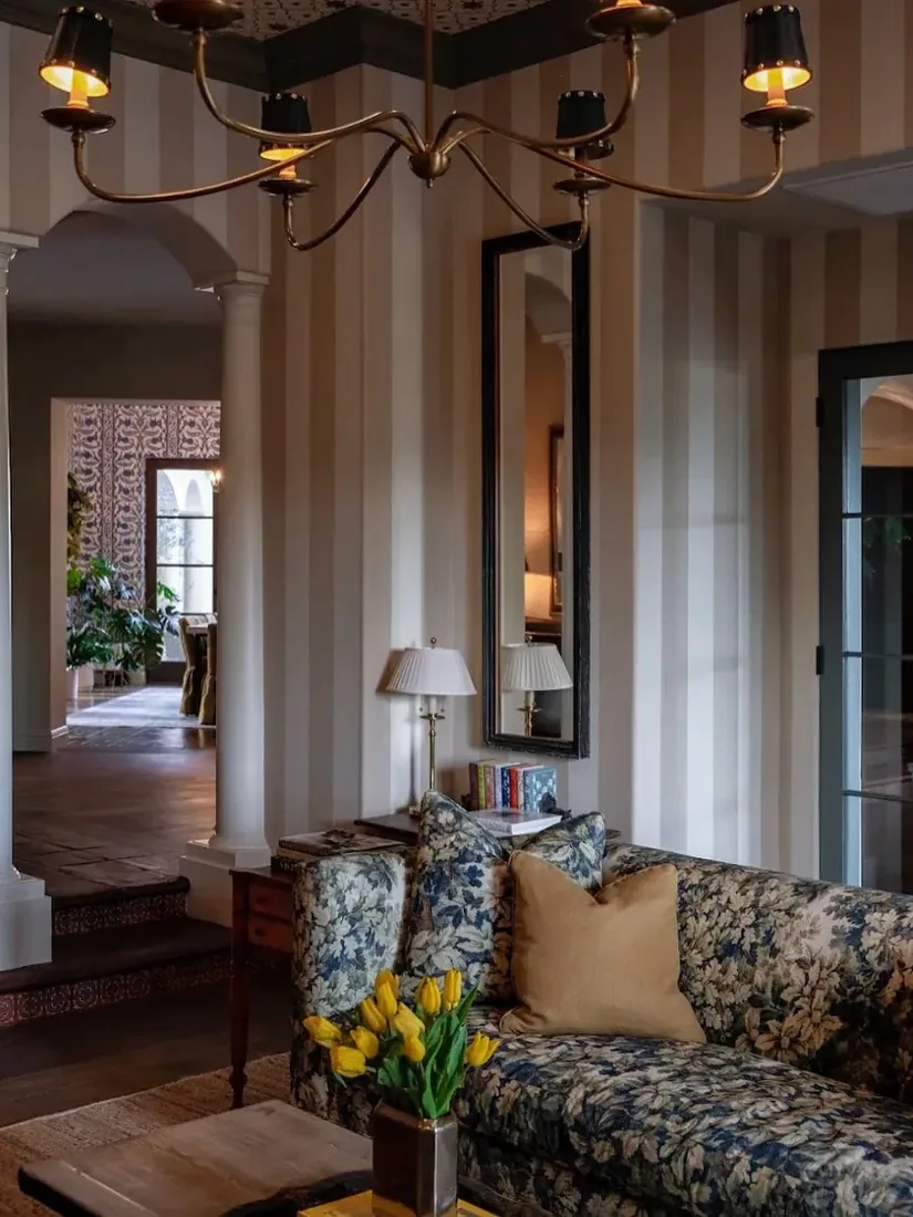 Floral sofa against striped wallpaper with plain woodwork