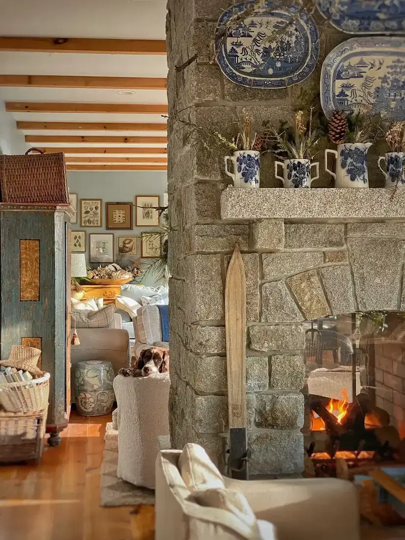 Floor to ceiling granite fireplace wall with blue and white pitchers of dried flowers on a stone mantel
