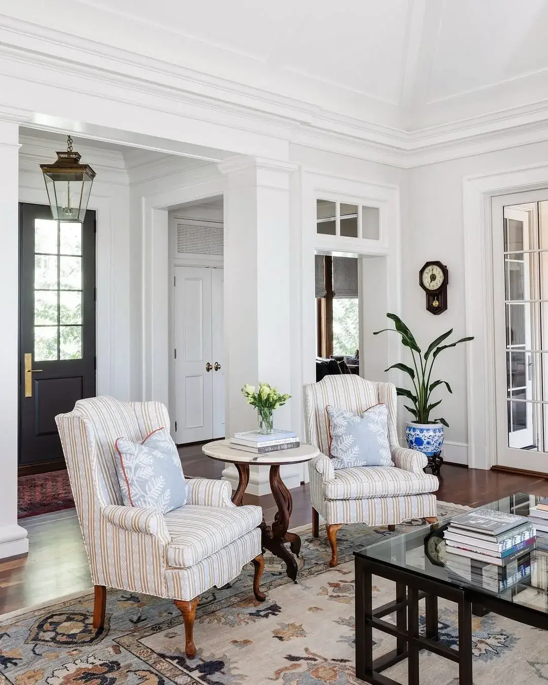 Striped armchairs on a floral rug in a white panelled room