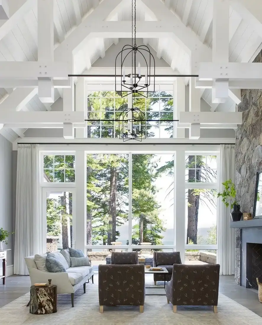 White vaulted living room with stone fireplace, linen sofa and garden view
