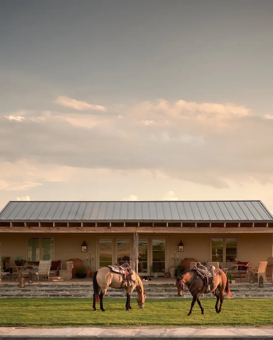 Ranch porch with horses grazing on the lawn beyond