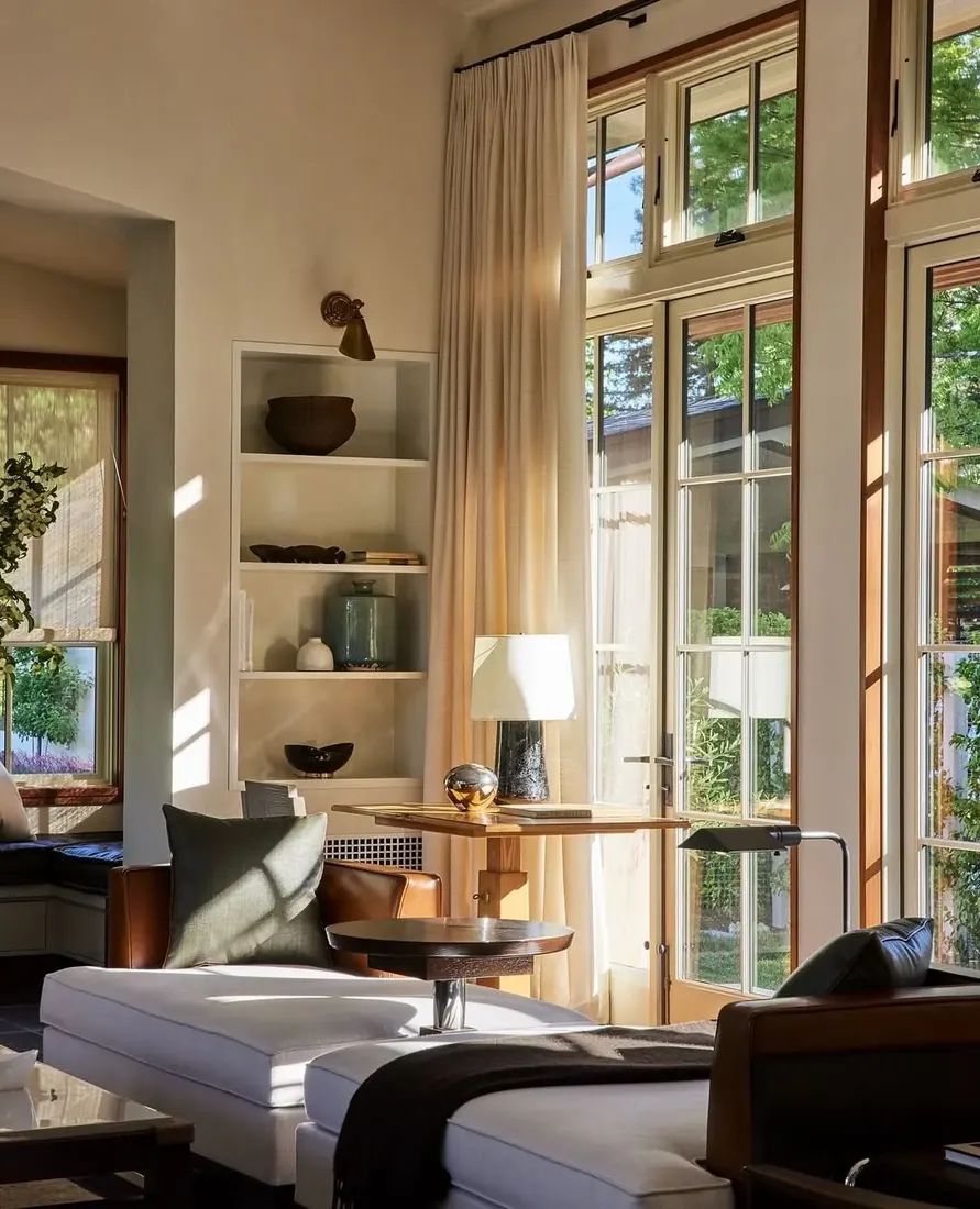 Sunlit corner with leather chairs, oak table and tall glazing